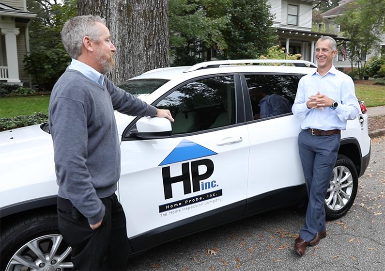 Jeff Luther, Founder of Home-Probe, and another man stand next to a white SUV with a Home-Probe logo decal on the side.